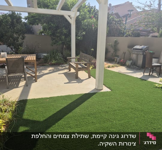גינה עם דשא סינטטי, שולחן עץ וכיסאות.